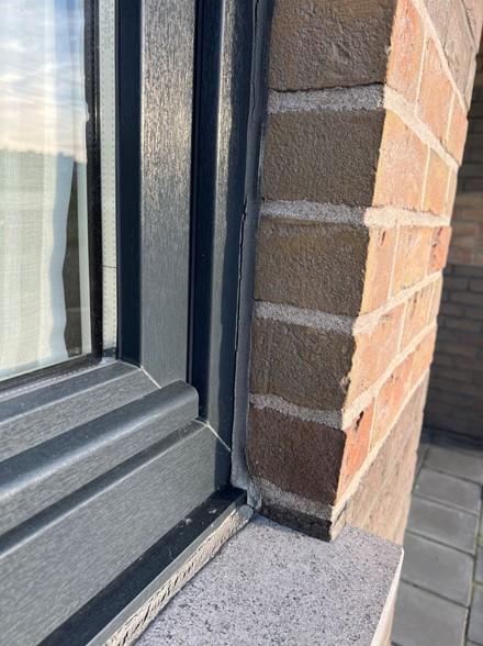 Kozijn met zichtbare kitrand tegen het metselwerk